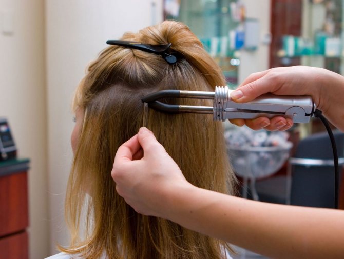 Девушка наращивает волосы в салоне