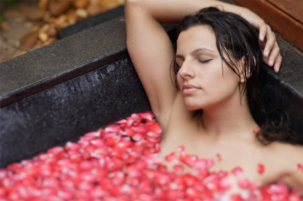 Девушка принимает ванну с лепестками роз