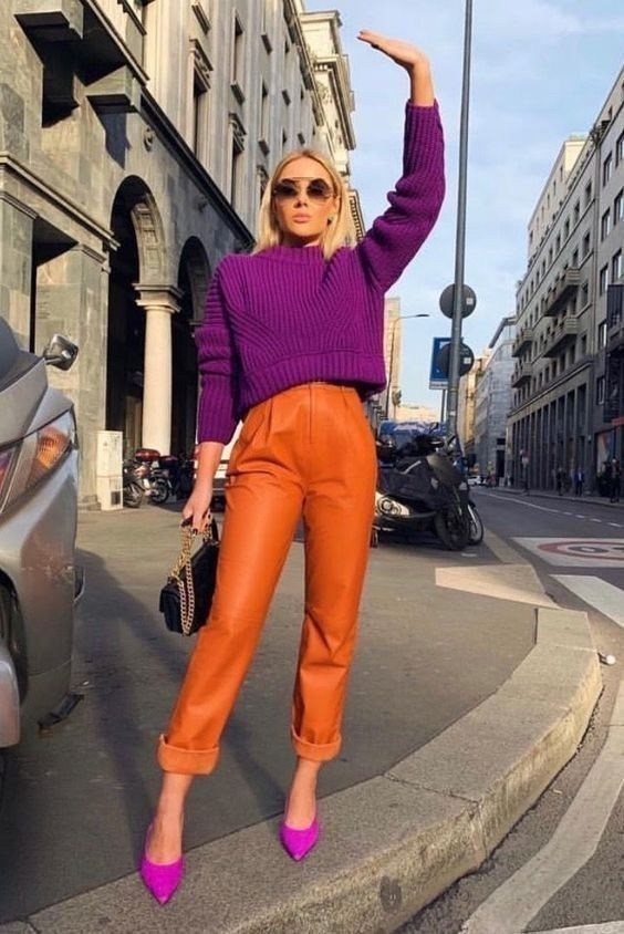 Девушка в оранжевых кожаных брюках, фиолетовый свитер и туфли на шпильке