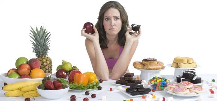 Девушка выбирает между сладостями и фруктами