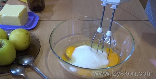 Для приготовления заливного пирога с кусочками яблок со сметаной - разбейте яйца в чашу и введите сахар