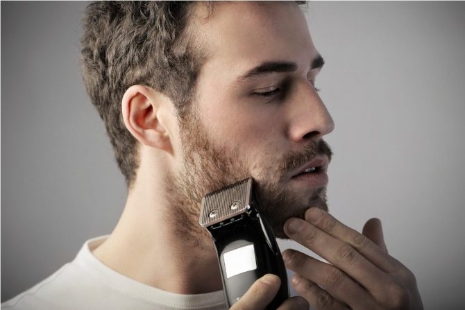 Мужчина бреет бороду электробритвой