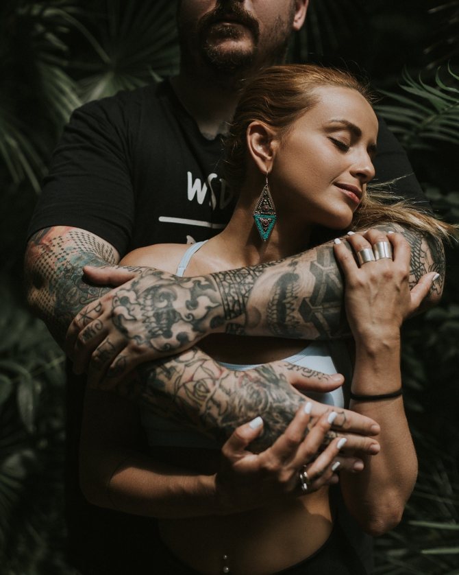 Мужчина с татуировками на руках обнимает женщину