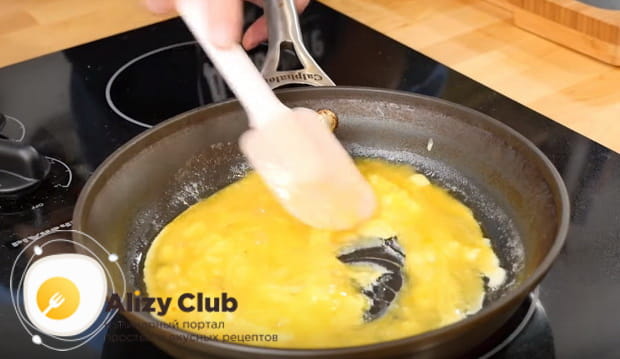 Выливаем на сковороду яйца и немного помешиваем омлет лопаткой