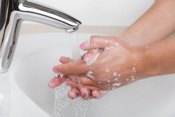 Женщина моет руки в воде из крана